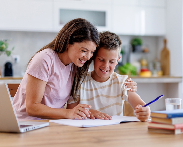Mother helping a child with homework at a sunlit table